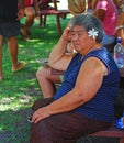 Cook Islander woman sitting on a bench enjoying the outdoor atmosphere with frangipani flower on the ear, Rarotonga, Cooks Islands