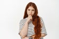 Image of thoughtful redhead teen girl squinting, touching chin, consider smth, thinking, making decision, ponder choices