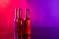 Image of three brown beer bottles with crown caps, with copy space on red and purple background Royalty Free Stock Photo