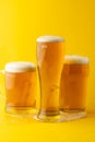 Image of three different full pint glasses of lager beer, with copy space on yellow background