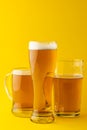 Image of three different pint glasses of lager beer, with copy space on yellow background