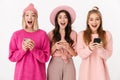 Image of three girls wearing pink clothes laughing and holding cellphones Royalty Free Stock Photo