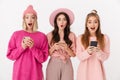 Image of three girls wearing pink clothes wondering and holding cellphones Royalty Free Stock Photo