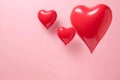 Image of three red heart-shaped balloons of different size floating with a pink background behind them, love is in the air,