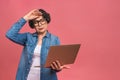 Image of tired depressed mature aged senior business woman standing isolated over pink background using laptop computer. Portrait Royalty Free Stock Photo