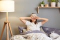 Image of tired sleepy woman with sleeping mask lying in bed and rubbing her eyes, being sleepless, having lack of sleep, wearing Royalty Free Stock Photo