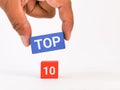 The word TOP 10 written on wooden cubes against white background with hand.