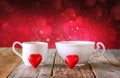 Image of tow red heart shape chocolates and couple cups of coffee on wooden table Royalty Free Stock Photo