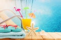 image of tropical and exotic fruit coctail over wooden table infront of swimming pool background