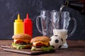 Image of two hamburgers, glasses, soccer ball, ketchup Royalty Free Stock Photo