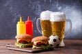 Image of two hamburgers, glasses, soccer ball, ketchup Royalty Free Stock Photo