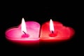 Two love heart candles on a black background