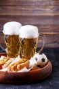 Image of two mugs of beer and hot dogs on wooden tray with football Royalty Free Stock Photo