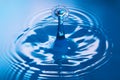 Two water drops crashing and creating ripples on clean blue water Royalty Free Stock Photo