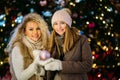 Image of two women on winter walk on background of decorated spruce