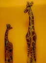 image of two wooden giraffes, one small and one large with a yellow background Royalty Free Stock Photo