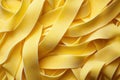 An image of uncooked yellow fettuccine pasta arranged in a close-up view, showcasing its smooth texture