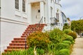Unique staircase leading to white door on building with bushes and tunnel view down sidewalk Royalty Free Stock Photo