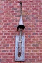 Unique street light protruding from a brick wall.