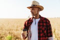 Image of unshaven adult man with wheat ear in her mouth drinking coffee