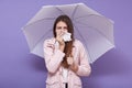 Image of upset sick young female using paper handkerchief, sneezing, having running nose, being ill, caught cold, holding umbrella Royalty Free Stock Photo