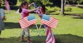 Image of usa flags over happy biracial boy and girl running with flags on grass Royalty Free Stock Photo