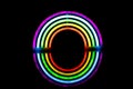 Image of vibrant neon glow sticks forming rainbow with reflection on black background and copy space Royalty Free Stock Photo