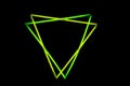 Image of vibrant triangles green neon glow sticks over black background with copy space Royalty Free Stock Photo