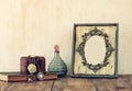 Image of victorian vintage antique classical frame, jewelry and perfume bottles on wooden table. filtered image Royalty Free Stock Photo