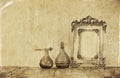 Image of victorian vintage antique classical frame and perfume bottles on wooden table. filtered image