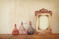 Image of victorian vintage antique classical frame and perfume bottles on wooden table. filtered image