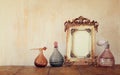 Image of victorian vintage antique classical frame and perfume bottles on wooden table. filtered image Royalty Free Stock Photo