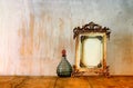 Image of victorian vintage antique classical frame and perfume bottles on wooden table. filtered image Royalty Free Stock Photo