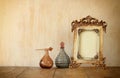 Image of victorian vintage antique classical frame and perfume bottles on wooden table. filtered image Royalty Free Stock Photo