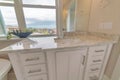 Image view of a part bathroom with a white frame window, marble sink and square mirror.