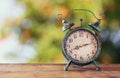 Image of vintage alarm clock on wooden table in front of abstract blurred background. retro filtered. Royalty Free Stock Photo