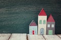 Image of vintage wooden colorful houses on wooden table in front of blackboard.