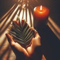 image 1:1 aspect ratio - hands held in prayer with a palm frond and a candle