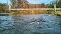 At water level over river with view of suspension bridge in late fall