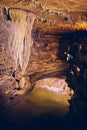 Waterfall in underground cave next to rock formations stalagmites and stalactites Royalty Free Stock Photo