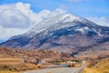 Western America snowy mountains huge by comparison to small paved road