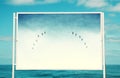 Image of white billboard on the beach with photo of flying birds over the sky. Royalty Free Stock Photo