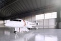 Image of White Matte Luxury Generic Design Private Jet parking in hangar airport. Concrete floor. Business Travel