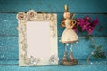 Image of white vintage blank frame and cute fairy princess on wooden table. vintage filtered with glitter overlay