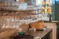 Image of wine glasses stacked on black metal hanging bar glass racks in a bar, nightclub or a restaurant with light shining