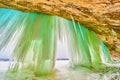 Winter ice cavern with tall sheets and icicles of blue and green ice