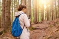 Image of woman backpacker trying to find her way, using mobile phone in forest, female going for walk in spring season, attractive Royalty Free Stock Photo