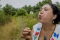 Image of a woman blowing a dandelion flower in a beautiful day