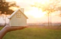 Image of woman holding small wooden house outdoors at sunset light. Royalty Free Stock Photo