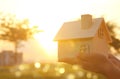 Image of woman holding small wooden house outdoors at sunset light. Royalty Free Stock Photo